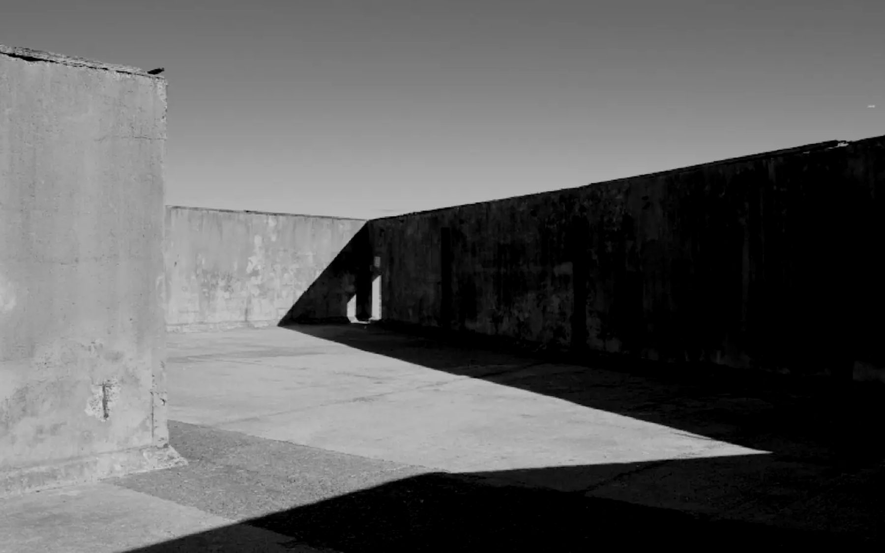 A long concrete wall casting a shadow across open ground